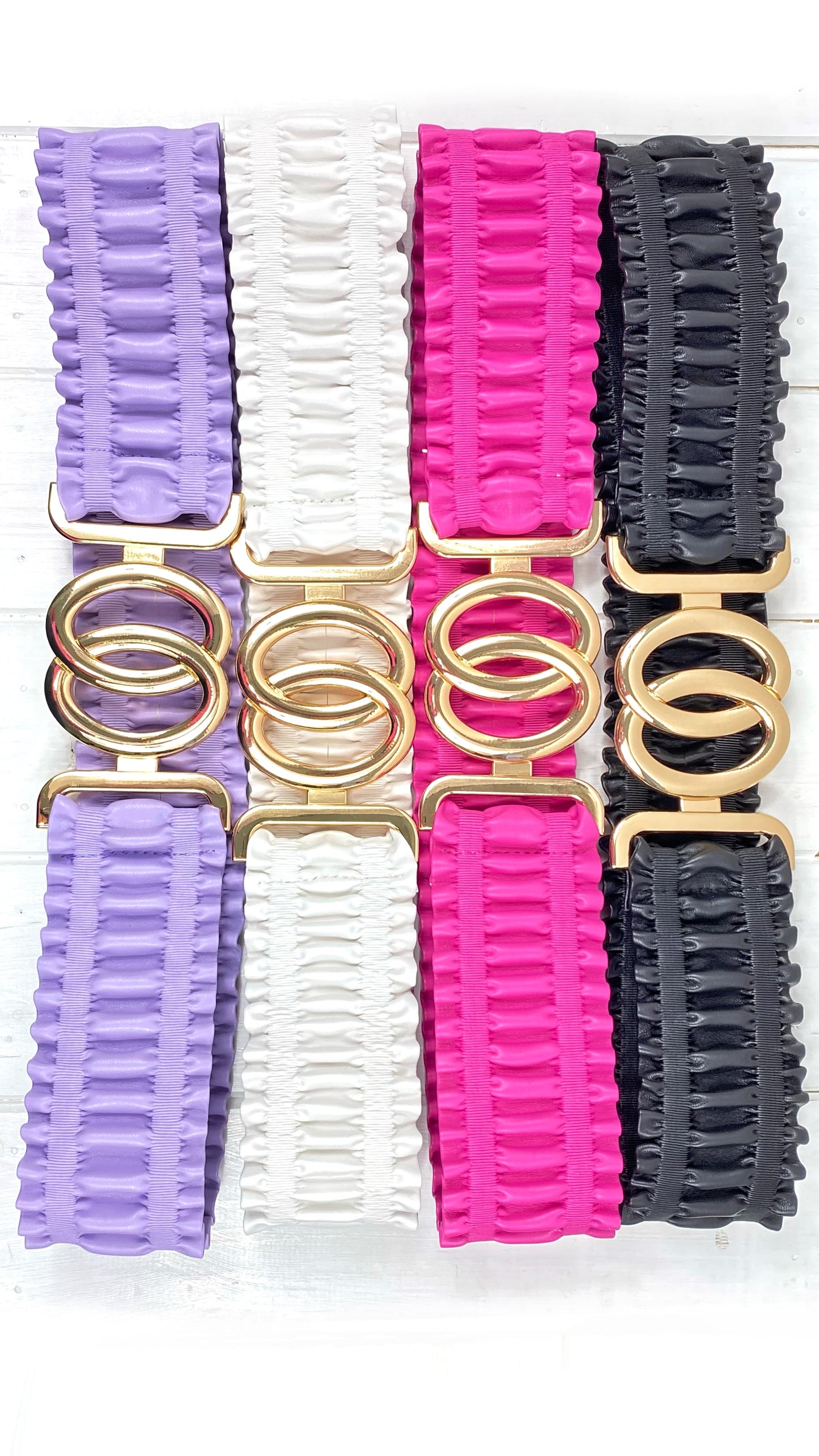 Cintura da donna effetto arricciato. 1 cinturino arricciato in ecopelle colore lilla , fibbia doppio cerchio oro. 2 cinturino arricciato in ecopelle bianco fibbia doppio cerchio oro. 3 cinturino arricciato in ecopelle fucsia fibbiia doppio cerchio oro. 4 cinturino arricciato in ecopelle nera fibbia doppio cerchio oro.